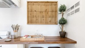 A kitchen with a wooden countertop, a corkboard, a potted plant, and two stools.