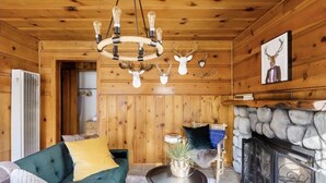 A cozy cabin interior with a green sofa, a fireplace, and wooden walls.