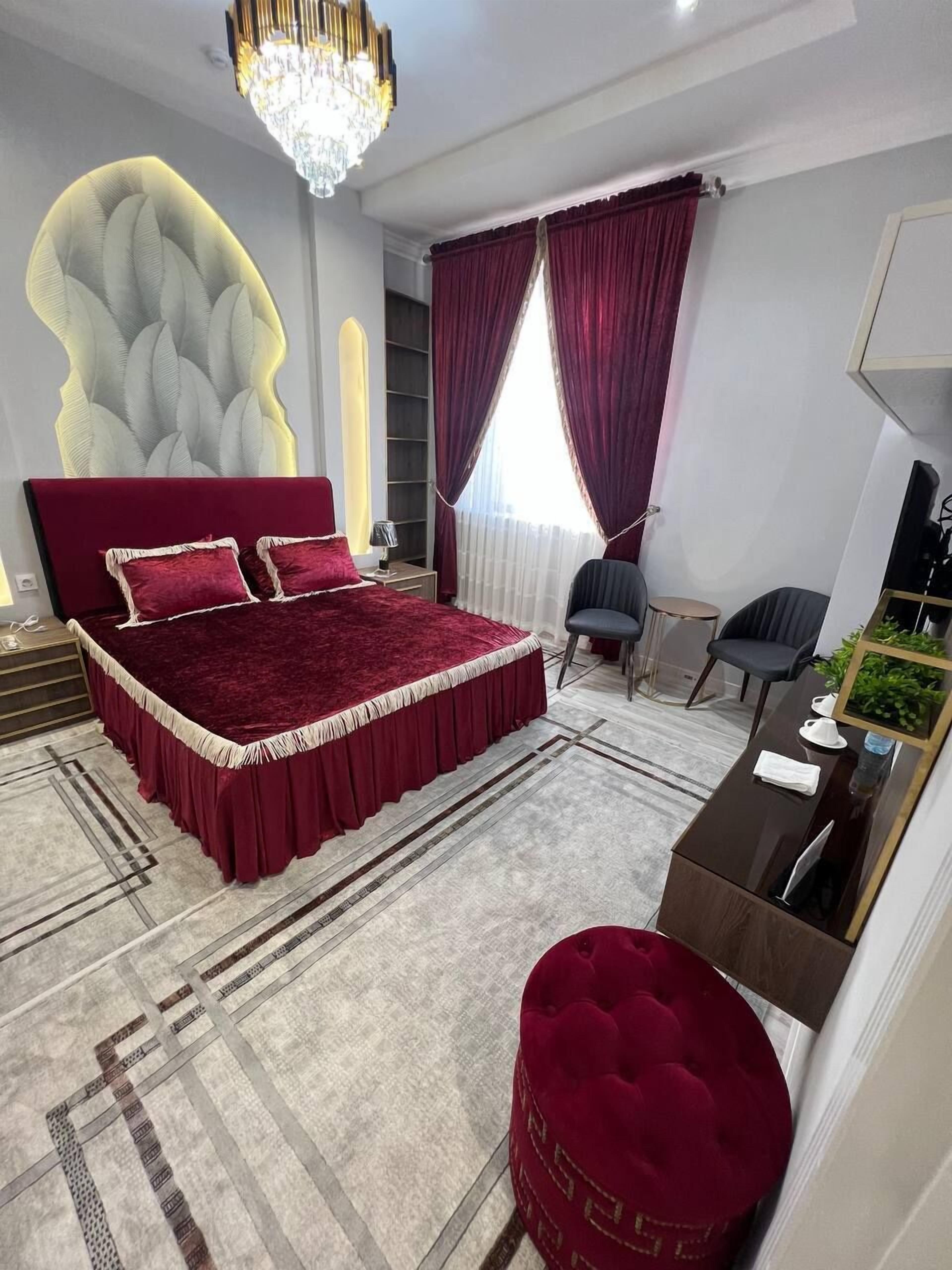 A modern bedroom with a large bed, a chandelier, and a desk with a mirror.