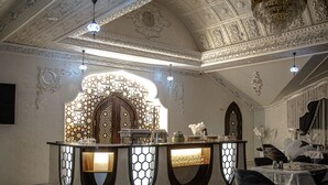 Um interior luxuoso com área de bar central, teto ornamentado e mobiliário elegante.