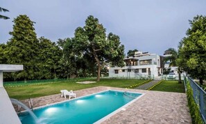 Ein modernes Haus mit Swimmingpool, umgeben von üppiger Vegetation und einem gepflegten Rasen.