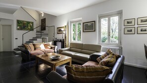 A modern living room with a staircase, two sofas, a coffee table, and a bookshelf. - Villa Visconta in Naresso Inferiore (Besana in Brianza)