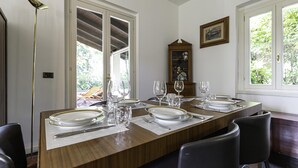 A dining table set with plates, glasses, and cutlery, surrounded by chairs, with a wooden cabinet and a framed picture on the wall. - Villa Visconta in Naresso Inferiore (Besana in Brianza)
