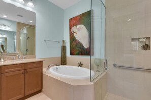 A modern bathroom with a glass-enclosed shower, a large bathtub, and a vanity with a mirror. - Villa Dominica is a luxurious ground floor home in the community, The Isles of Collier Preserve. (Naples)