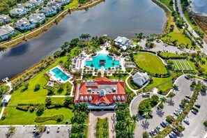 An aerial view of a resort with a central swimming pool, a separate pool, and a large building with a red roof. - Villa Dominica is a luxurious ground floor home in the community, The Isles of Collier Preserve. (Naples)