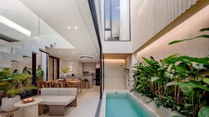 En modern inredning med ett matområde, en pool och en trappa som leder upp till en övre våning.