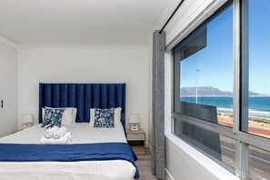 A hotel room with a large bed, two bedside tables, and a view of the ocean.