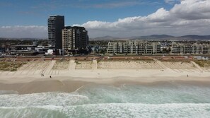 Eine Küstenstadt mit Hochhäusern, einem Strand und Blick auf entfernte Berge.