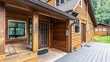Step into a cozy cabin-style retreat with a welcoming entrance and expansive deck area perfect for relaxation or outdoor activities.