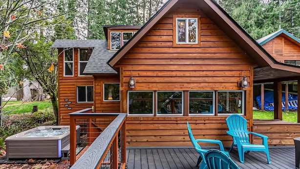 A wooden cabin with a deck, two Adirondack chairs, and a hot tub. - Riverfront Cabin w/Hot Tub : Near Mt. Rainier Sunrise entrance (Enumclaw)