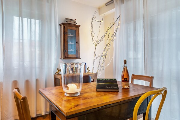 A dining table with a candle, a bottle, and a book.