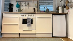 Cozinha equipada com fogão, forno, pia e um frigorífico pequeno.