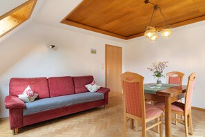Une pièce avec un canapé rouge, une table à manger en bois et des chaises.