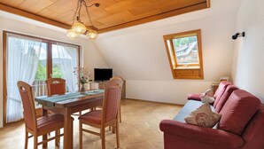 Uma sala de jantar com mesa e cadeiras de madeira, uma televisão e um sofá vermelho.