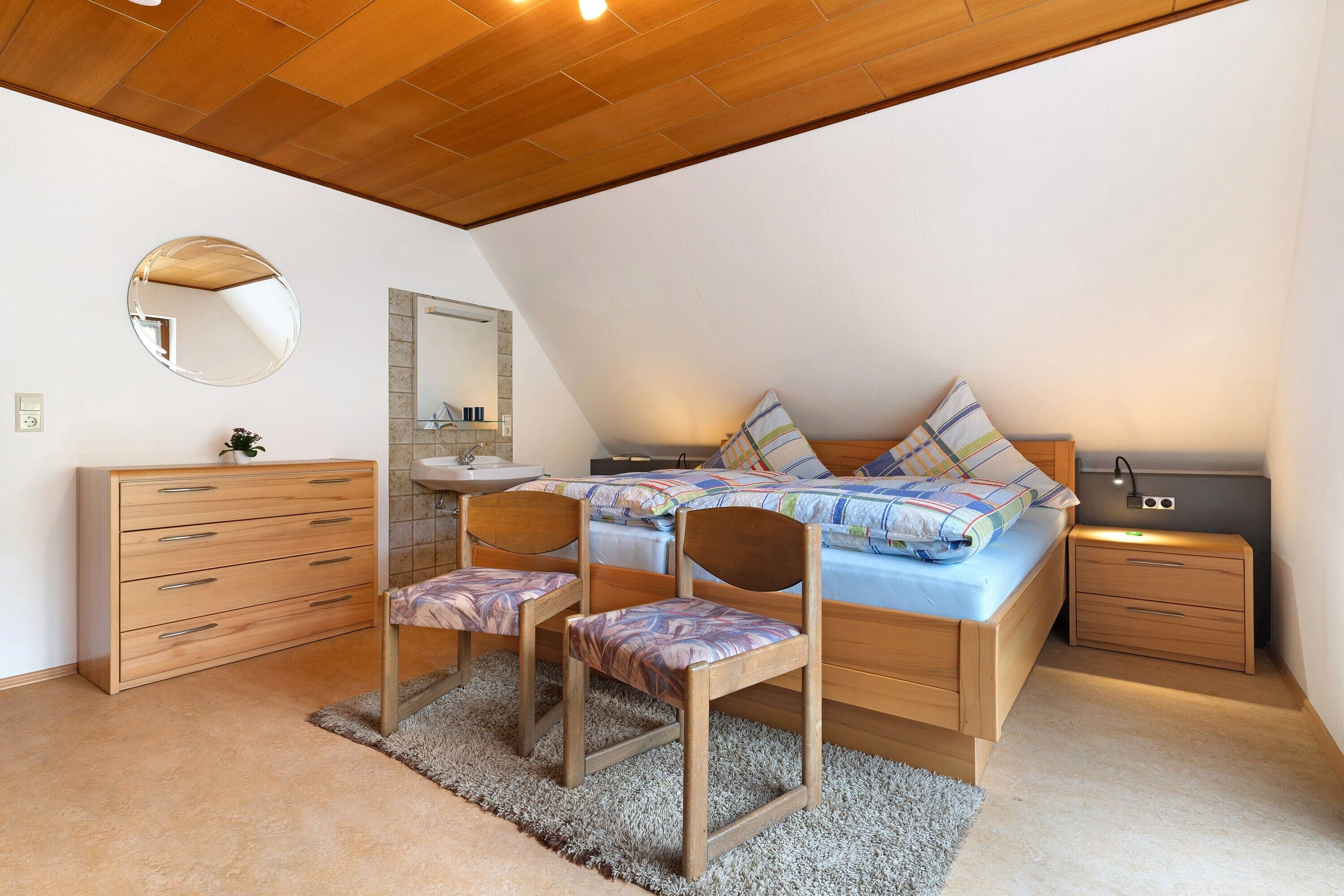Une chambre à coucher avec un lit, deux chaises, une commode, un miroir et une table de chevet.