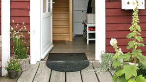 A wooden front door, a number '7' sign, a doormat, and a small porch area with plants. - Apartment 'Ferienwohnung Traumblick' with Balcony and Wi-Fi (Reesdorf)