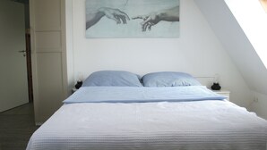 A bedroom with a bed, pillows, a nightstand, a lamp, and a painting on the wall. - Apartment 'Ferienwohnung Traumblick' with Balcony and Wi-Fi (Reesdorf)