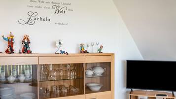 Ein Zimmer mit einem Holzschrank, der Gläser, einen Flachbildfernseher und dekorative Figuren beherbergt.
