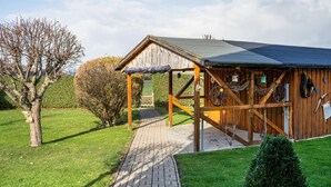 Een rustiek houten gebouw met een overdekte veranda, een pad van baksteen dat er naartoe leidt en een verzorgd gazon.