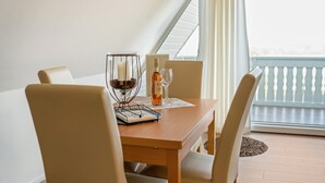 Een eettafel met stoelen, kandelaar, fles en glazen op een balkon met een hekwerk.