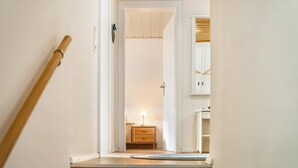 Een trap die leidt naar een slaapkamer met een houten vloer, een nachtkastje met een lamp en een kledingkast.