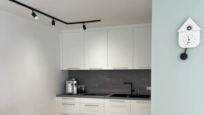 Una cocina moderna con armarios blancos, una mesa de comedor de madera y un reloj en la pared.