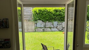 Una habitación con puerta de vidrio corrediza que da a un patio con una silla y un muro de piedra.