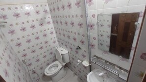 Un baño con azulejos de diseño floral, inodoro, lavamanos y ducha.