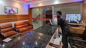 Una zona de recepción con mostrador de mármol, sofás, un televisor y un monitor de computadora.