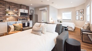 A modern hotel room with a kitchen area, a large bed, a sofa, and a small table. - Cozy, Bran New Private fully furnished studio downtown Chilliwack.  (Chilliwack)
