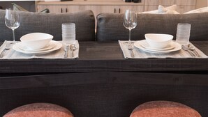 A dining area with two sets of white dinnerware on dark placemats, each set accompanied by a glass and a spoon. - Cozy, Bran New Private fully furnished studio downtown Chilliwack.  (Chilliwack)