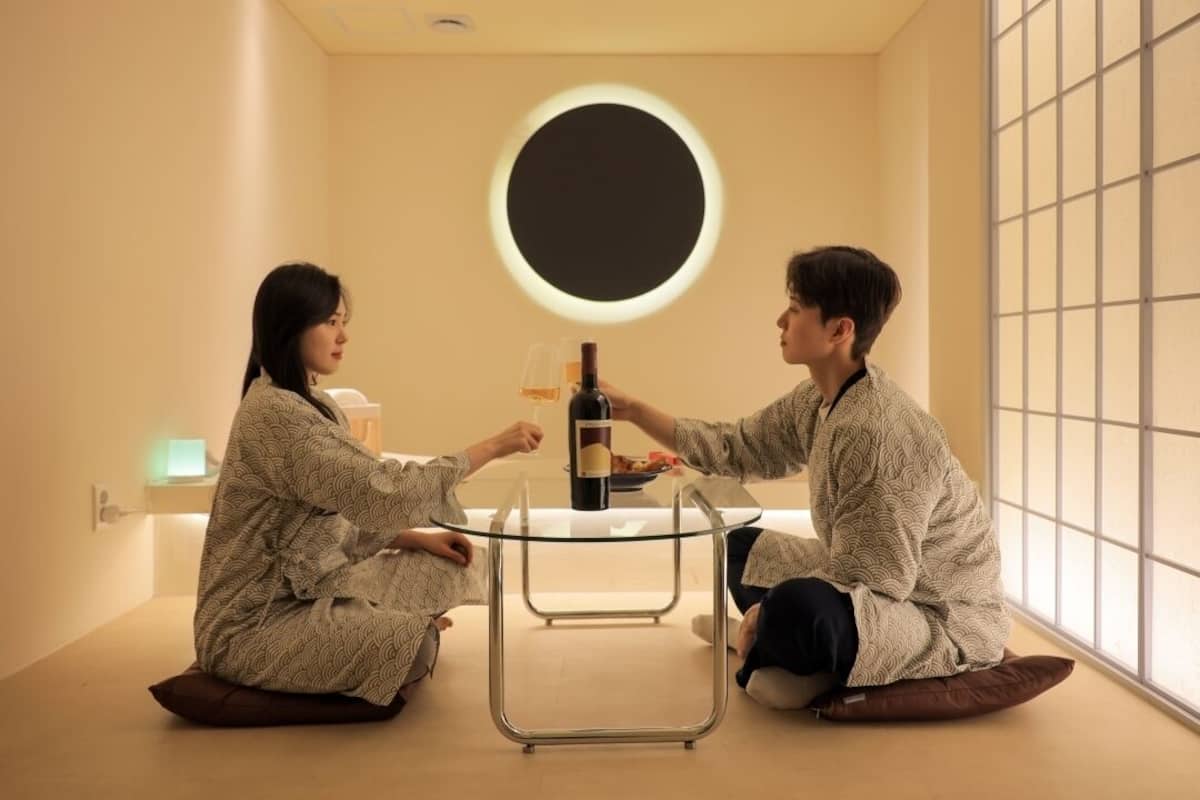 Two people sitting on the floor, facing each other, with a table between them.