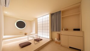 A minimalist room with a bed, a glass table, a round mirror, a window with a view, and a wardrobe. - Anook Ryokan Yosuriguri Hotel (Cheonan)