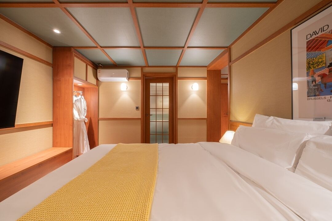 Une chambre d’hôtel avec un grand lit, un plafond en bois et une affiche accrochée au mur.