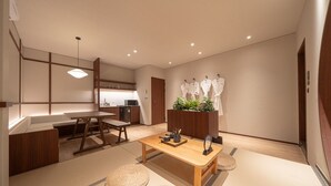 A modern, minimalist living room with a wooden dining table, a sofa, and a kitchen area in the background. - Anook Ryokan Yosuriguri Hotel (Cheonan)