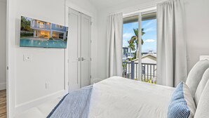 Un dormitorio con una cama grande, una ventana con cortinas y vistas a una piscina y edificios.