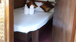 A single bed with white bedding, two decorative pillows, a hanging white light fixture, and a framed picture on the wall. - Zhaya's Beach and Cottages (El Nido)