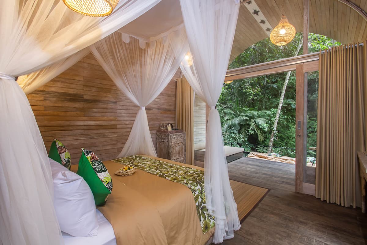 Un dormitorio con cama con dosel, paredes de madera y vistas al exterior.