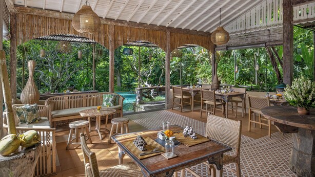 A spacious outdoor dining area with wooden furniture, a view of a lush garden, and a pool in the background. -  Sacred Beji by GenuineHost (Payangan)