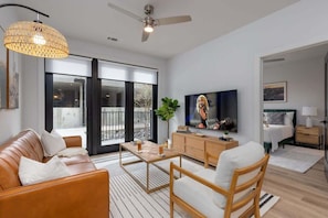 A modern living room with a sofa, coffee table, TV, and a balcony view.