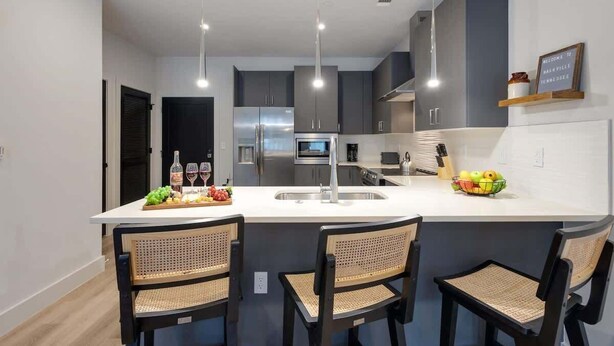 A modern kitchen with a central island, bar stools, and a sign welcoming to Nashville, Tennessee. - Savanna-Odyssey at the Park- Pool & Full Gym (Nashville)
