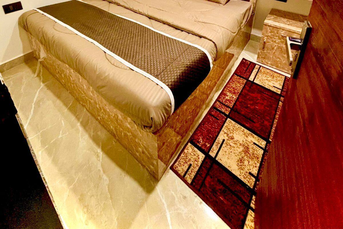 Ein Schlafzimmer mit Bett, Nachttisch, Kleiderschrank und einem gemusterten Teppich.