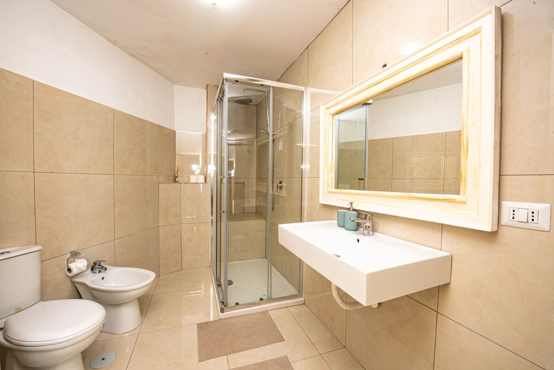 Une salle de bain avec une douche à parois de verre, un lavabo blanc et un grand miroir.