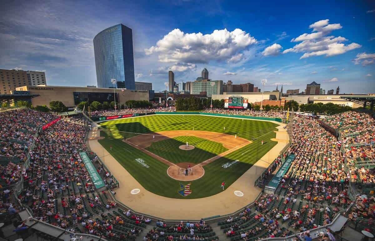 A large stadium with multiple seating tiers, a baseball diamond, and a city skyline in the background.