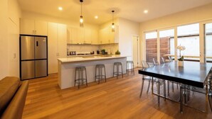 Una cocina moderna con una isla central, taburetes de bar y una mesa de comedor con sillas.