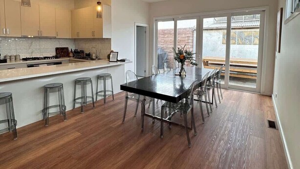 Una cocina moderna con zona de comedor, piso de madera y ventanas amplias.
