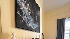 Una habitación con chimenea, un cuadro sobre ella y una ventana con cortinas.