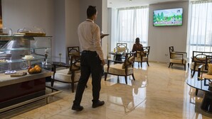 Un hall d’hôtel comprenant un espace buffet, un téléviseur diffusant un dessin animé et un coin salon avec des chaises et des tables.