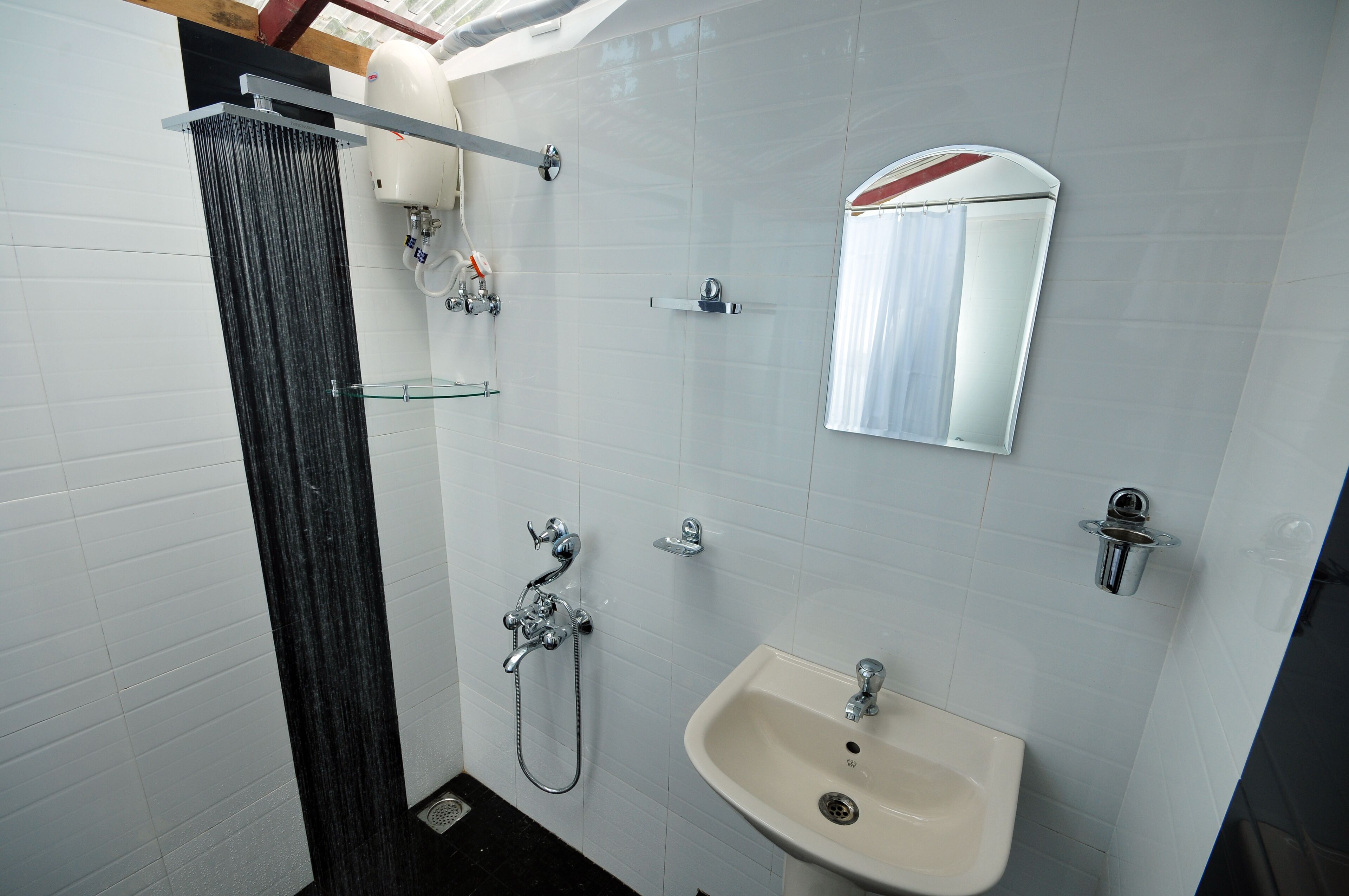 A bathroom with a shower, a sink, a mirror, and a toilet.