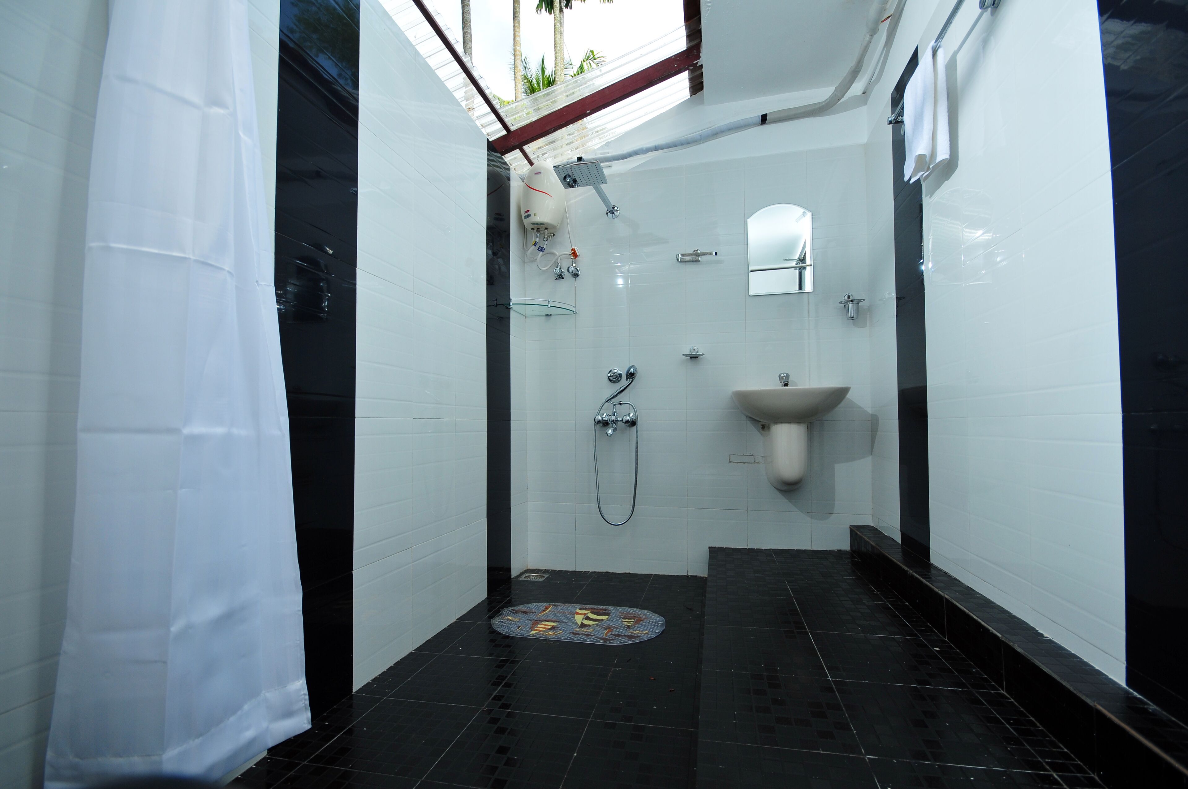 Een kleine, smalle badkamer met een douche, wastafel en spiegel.